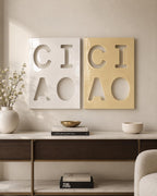 Two rectangular wall plaques, one white and one light yellow, each featuring cut-out letters and shapes. The white plaque displays the letters C, I, A and a circle, while the yellow plaque mirrors this design with the same cut-out layout.