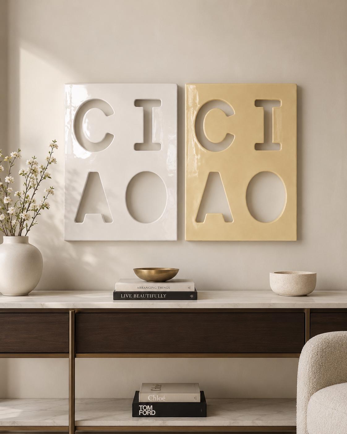 Two rectangular wall plaques, one white and one light yellow, each featuring cut-out letters and shapes. The white plaque displays the letters C, I, A and a circle, while the yellow plaque mirrors this design with the same cut-out layout.