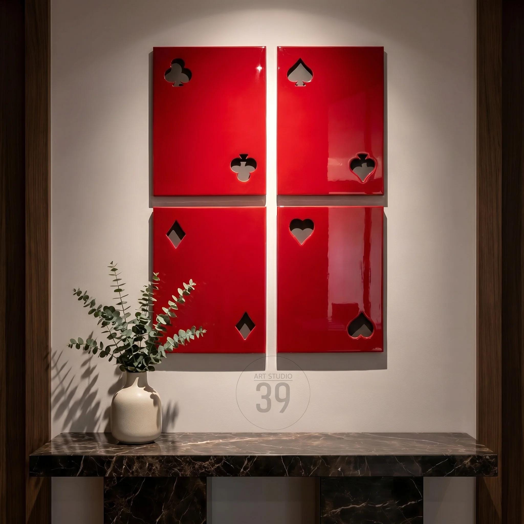Four rectangular wall panels in a glossy red finish, each featuring a cutout representing a playing card suit. The top left panel shows a club, the top right a spade, the bottom left a diamond, and the bottom right a heart.