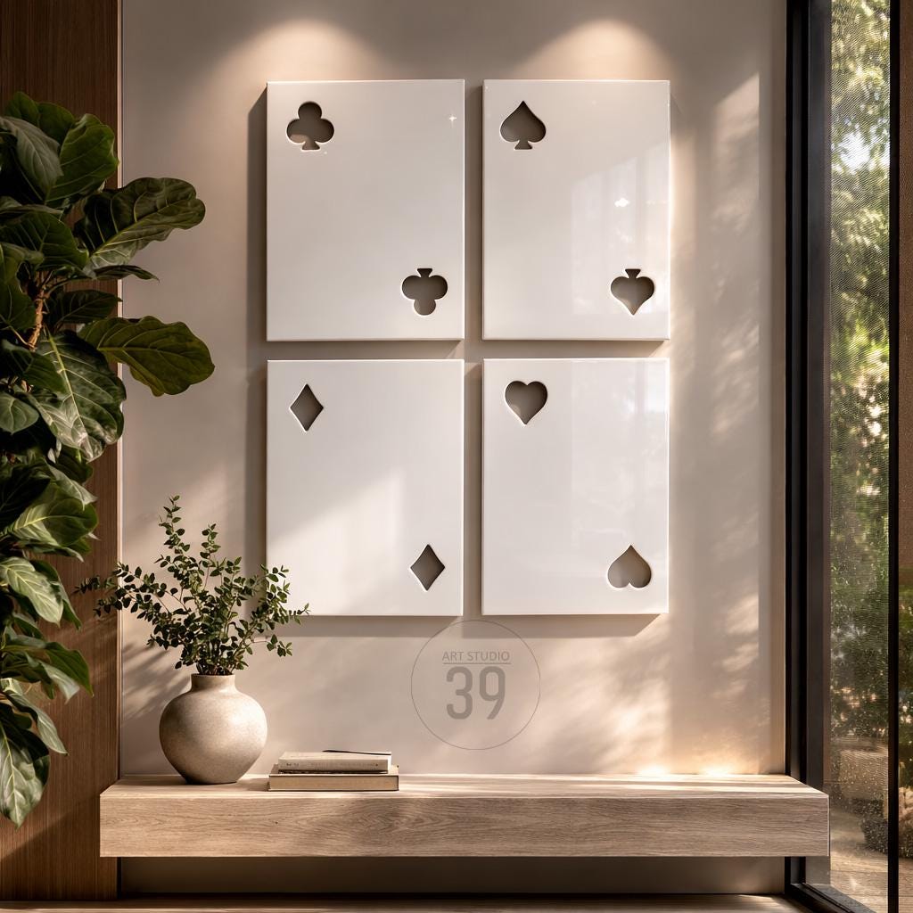 Four rectangular white wall panels arranged in a grid, each featuring cut-out shapes representing playing card suits: clubs, spades, diamonds, and hearts. The panels have a smooth, glossy finish and are mounted on a neutral-toned wall.