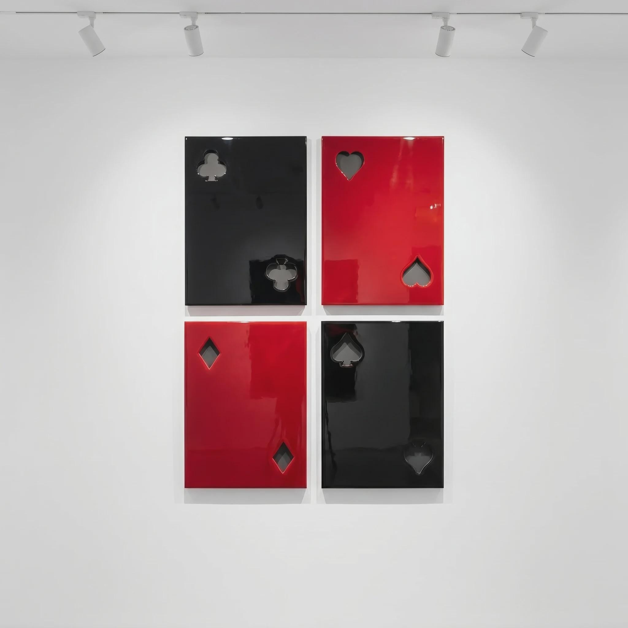 Four rectangular wall panels arranged in a grid, each featuring a glossy finish and a cutout representing a playing card suit. The top left is black with a club, top right is red with a heart, bottom left is red with a diamond, and bottom right is black with a spade.